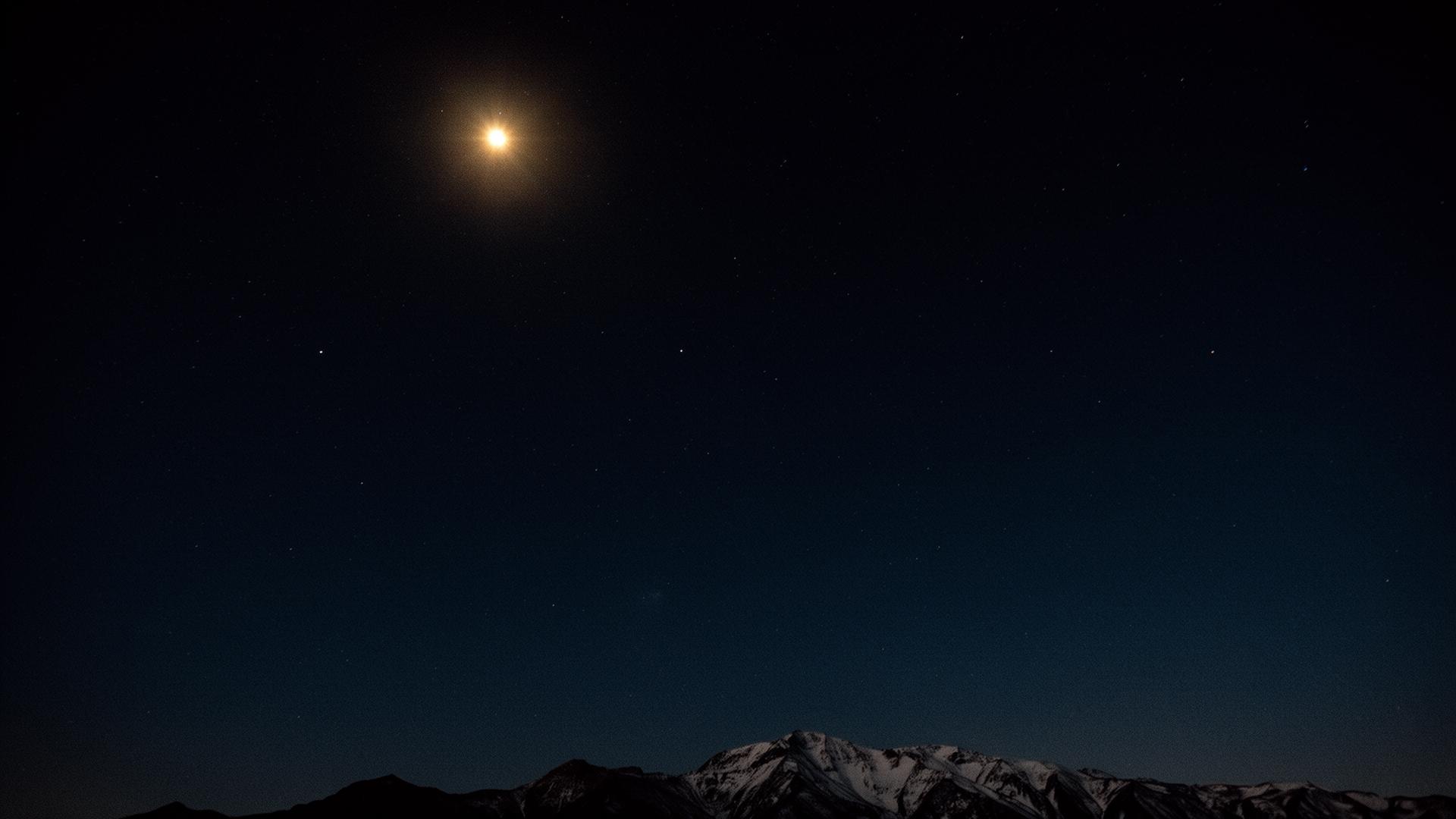 A dark night sky with the North Star above a faint mountain ridge